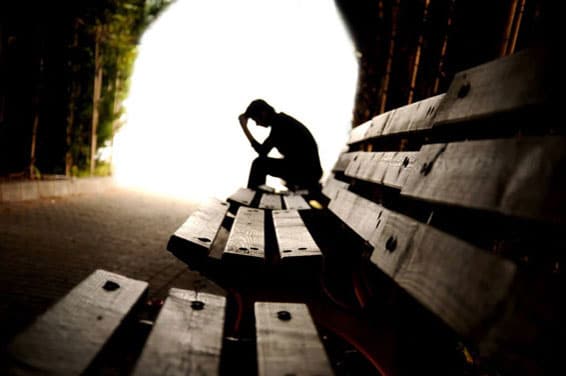 Depressed man sitting on bench outside