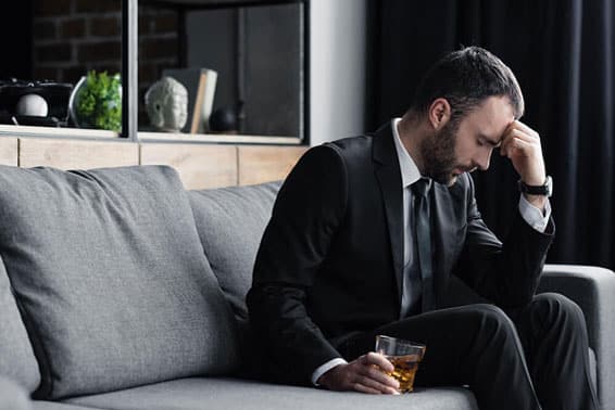 A depressed man sitting with an alcoholic drink