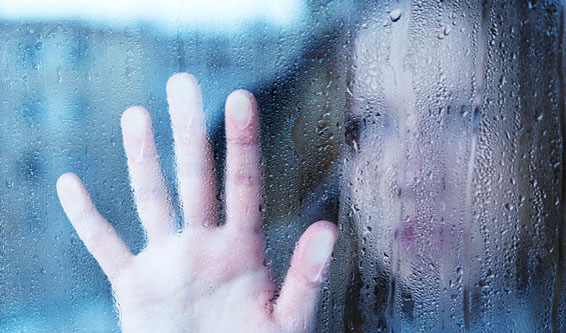 Person with hand pressed against rain covered window