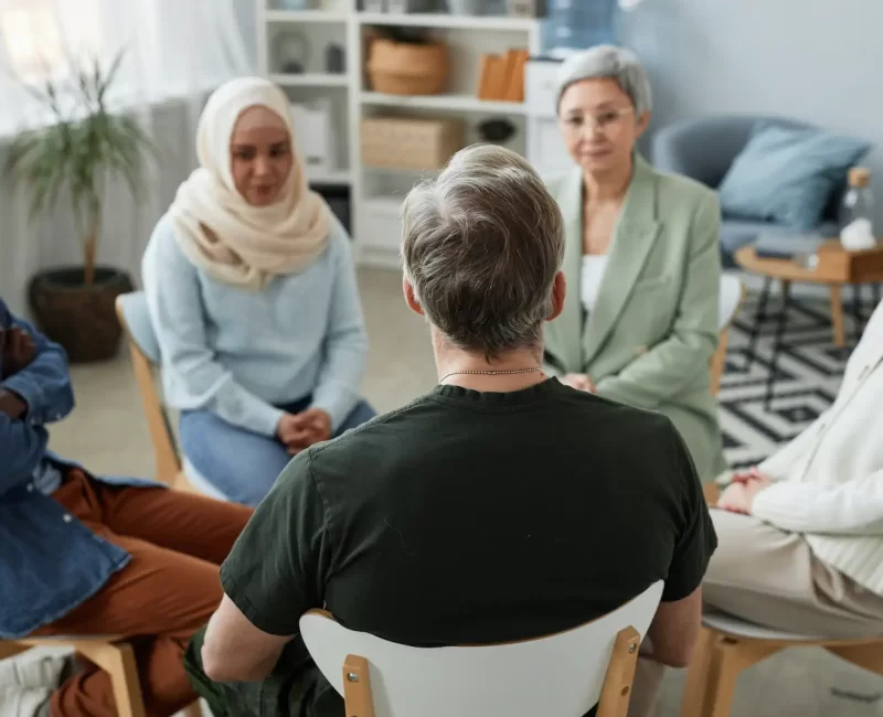 focus-rear-view-mature-male-patient-counselor-sitting-front-group focus-rear-view-mature-male-patient-counselor-sitting-front-group
