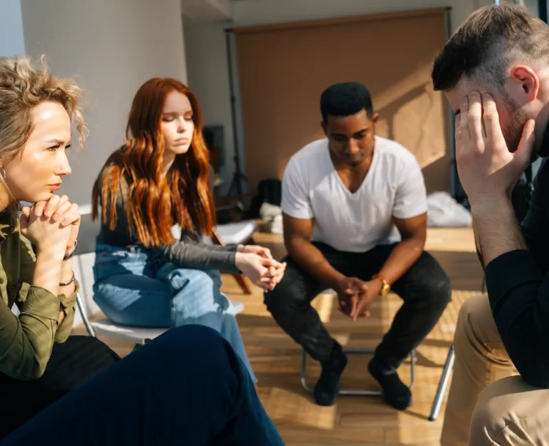 frustrated-young-man-sharing-problem-sitting-circle-during-group-interpersonal-therapy-session-sad-depressed-male-smiling-telling-sad-story-mental-problem-other-patients frustrated-young-man-sharing-problem-sitting-circle-during-group-interpersonal-therapy-session-sad-depressed-male-smiling-telling-sad-story-mental-problem-other-patients
